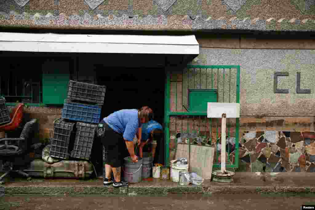 Habitantes del barrio limpian muebles y otros enseres que terminaron llenos de lodo producto del desbordamiento del río Guaire.