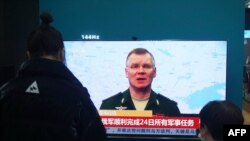Residents watch a TV screen showing news about conflict between Russia and Ukraine at a shopping mall in Hangzhou, in China on Feb. 25, 2022. 