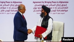 Mullah Abdul Ghani Baradar, Taliban delegation leader, and Zalmay Khalilzad, U.S. envoy for peace in Afghanistan, shake hands after signing an agreement between members of Afghanistan's Taliban and the U.S. in Doha, Qatar, Feb. 29, 2020.