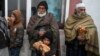 FILE - Recipients of free bread, distributed as part of a campaign to combat hunger, are pictured in front of a bakery in Kabul, Afghanistan, Jan. 18, 2022.