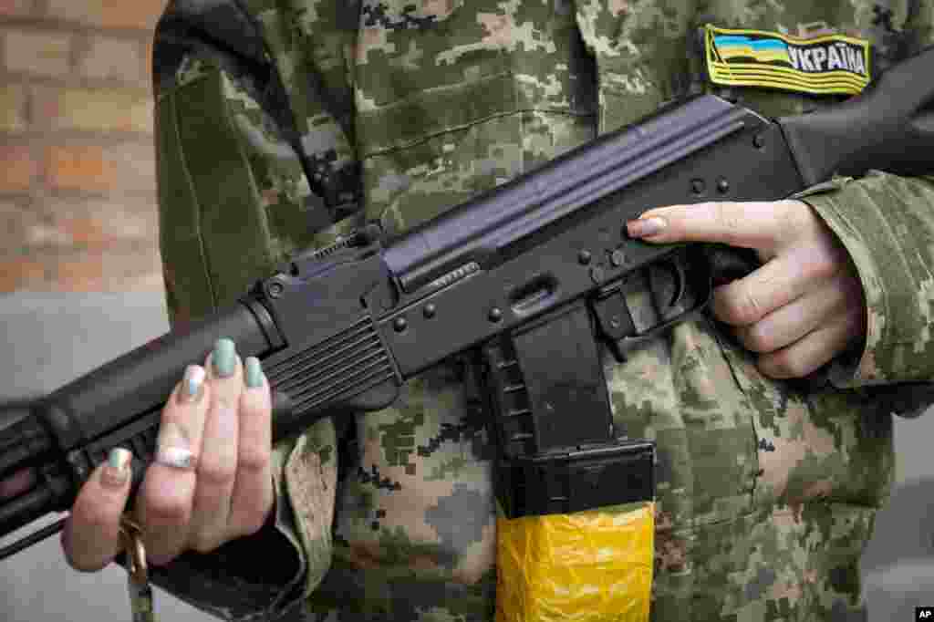 Вооружена жена од цивилната одбрана држи автоматска пушка „Калашников“ додека патролирала на празна улица поради полицискиот час во Киев, Украина, недела, 27 февруари 2022 година. Украински функционер вели дека избувнале улични борби во вториот по големина украински град Харков. Руските трупи, исто така, извршија зголемен притисок врз стратешките пристаништа на југот на земјата по бранот напади врз аеродромите и постројките за гориво на други места, кои се чинеше дека означуваа нова фаза од руската инвазија. (АП/ Ефрем Лукатски)