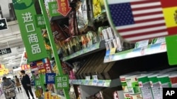 Seorang perempuan mendorong kereta belanja dekat jajaran produk-produk impor dari AS di sebuah supermarket di Beijing, 2 April 2018. 