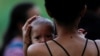 Una mujer migrante sostiene a su hijo mientras los solicitantes de asilo se reúnen para cruzar el río Bravo y entregarse a los agentes de la Patrulla Fronteriza estadounidense antes de que finalice el Título 42, en Matamoros, México, el 10 de mayo de 2023