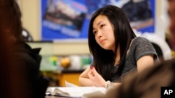 FILE - A student from South Korea takes notes during a physics class in Columbia, Mo., Feb. 27, 2012.