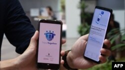新加坡政府科技局工作人员展示新加坡为应对新冠病毒疫情新推出的接触者追踪智能手机APP（2020年3月20日），这款APP使用蓝牙技术。