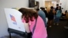 ARCHIVO - Una votante se inclina hacia la cabina mientras emite su voto en el último día de votación anticipada del estado para las elecciones intermedias de 2022 en Chapel Hill, Carolina del Norte, el 5 de noviembre de 2022.