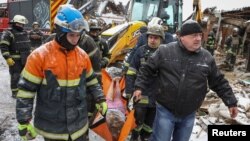 Spasioci evakuišu telo civila poginulog u ruskom raketnom udaru na zgradu u kojoj je živeo, u gradu Zmijiev, u regionu Harkova, Ukrajina, 8. januara 2024.
