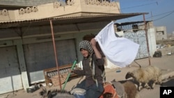 Un homme montre un drapeau blanc alors qu'il s'enfuie d'une zone de conflit à Gogjali, à l'est de Mosul, Irak, le 5 novembre 2016. 