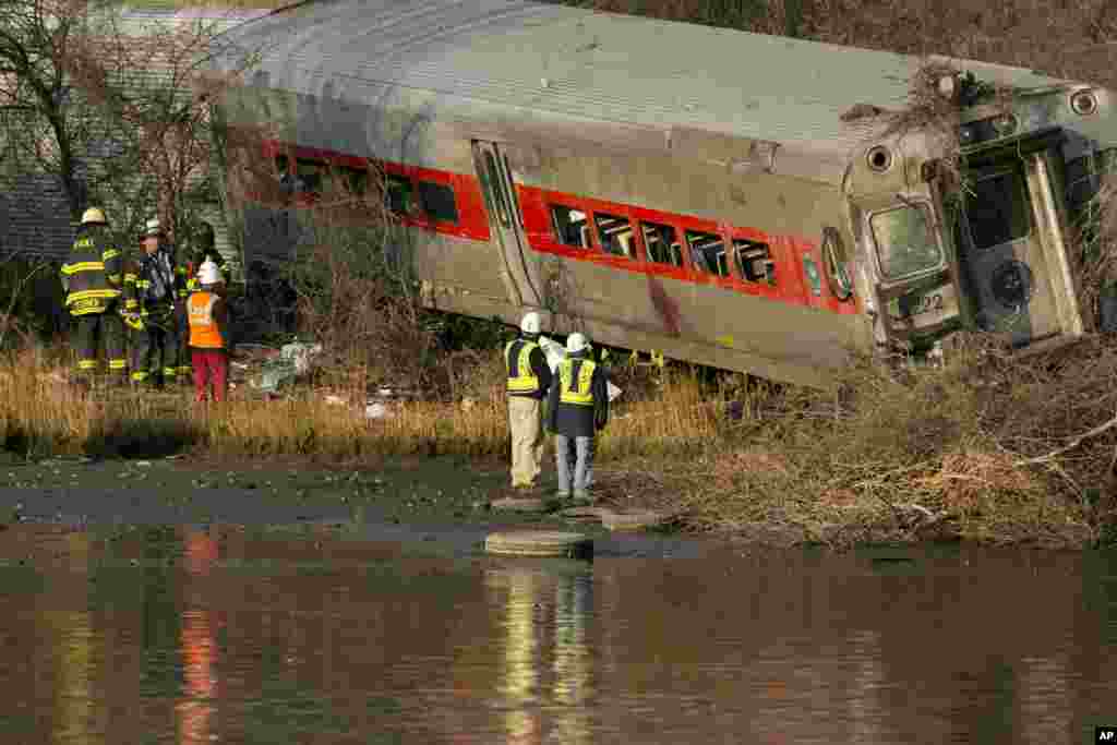 Para pejabat bersama Dewan Keamanan Transportasi Nasional memeriksa kereta komuter Metro-North yang tergelincir dan hampir jatuh ke sungai Harlem, 1 Desember 2013 di Bronx, New York.