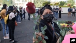 Una mujer entrega rosas a víctimas de violaciones de derechos humanos durante la guerra civil de Guatemala frente a la Corte Suprema de Justicia en Ciudad de Guatemala el lunes 24 de enero de 2022.