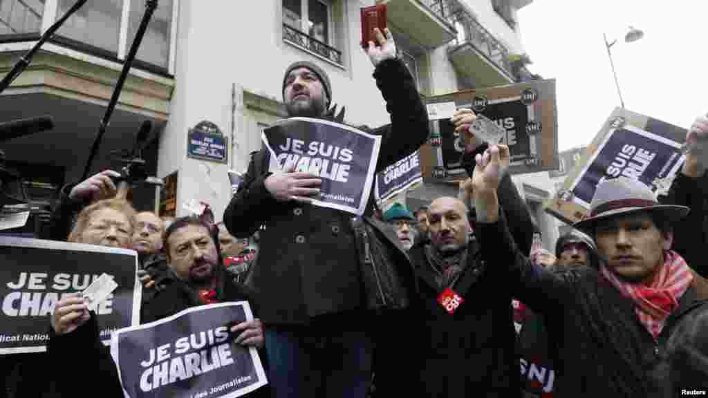 Les journalistes tiennent des pancartes mentionnant «Je suis Charlie" et leurs cartes de presse pendant une minute de silence devant les bureaux parisiens de journal hebdomadaire satirique Charlie Hebdo à Paris, le 8 janvier 2015