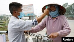 越南一名卫生工作者正在检测一名农民的体温（2020年2月12日）。