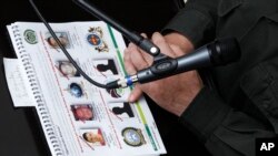 ARCHIVO - El jefe de la Policía Nacional de Colombia, el general José Roberto León, sostiene un documento policial que muestra las fotos de cuatro hombres que han sido capturados, durante una conferencia de prensa en la sede de la policía en Bogotá.