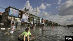 Seorang wanita menggunakan ban pelampung saat meninggalkan daerah yang terendam air di Bangkok (26/10).