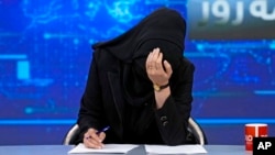 ARHIVA - TV voditeljka Katere Ahmadi spušta glavu dok čita vesti na stanici Tolo News u Kabulu, 22. maja 2022, nakon što su talibanski vladari odlučili da sve voditeljke na televiziji moraju da pokriju lice dok su u programu.