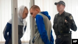 Russian Sgt. Vadim Shishimarin listens to his translator during a court hearing in Kyiv, Ukraine, May 23, 2022. 