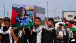 FILE - Students carry a mock coffin as they hold a symbolic funeral for slain Al Jazeera journalist Shireen Abu Akleh, at al-Azhar University in Mughraqa, central Gaza Strip, May 16, 2022. 