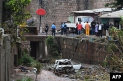 Oficiales de la Policía Nacional y lugareños observan los daños causados por las fuertes lluvias en Tegucigalpa, el 20 de mayo de 2022.