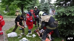Petugas paramedis dan layanan darurat tampak menolong seorang pria yang luka tertembak di wilayah Kharkiv, Ukraina, pada 26 Mei 2022. (Foto: AFP/Sergey Bobok)
