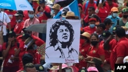 Empleados del Sindicato de Trabajadores del Instituto Hondureño del Seguro Social sostienen un cartel de la líder indígena asesinada Berta Cáceres durante la manifestación del Primero de Mayo (Día del Trabajo) en San Pedro Sula, Honduras, el 1 de mayo de 2022.