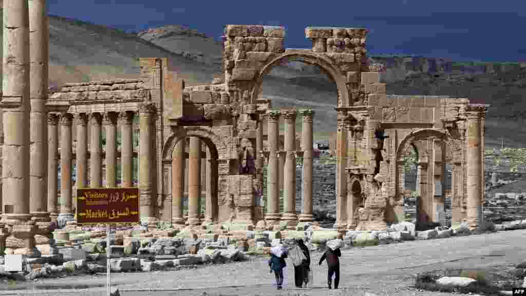 A picture taken on March 14, 2014 shows Syrian citizens walking in the ancient oasis city of Palmyra, 215 kilometres northeast of Damascus.