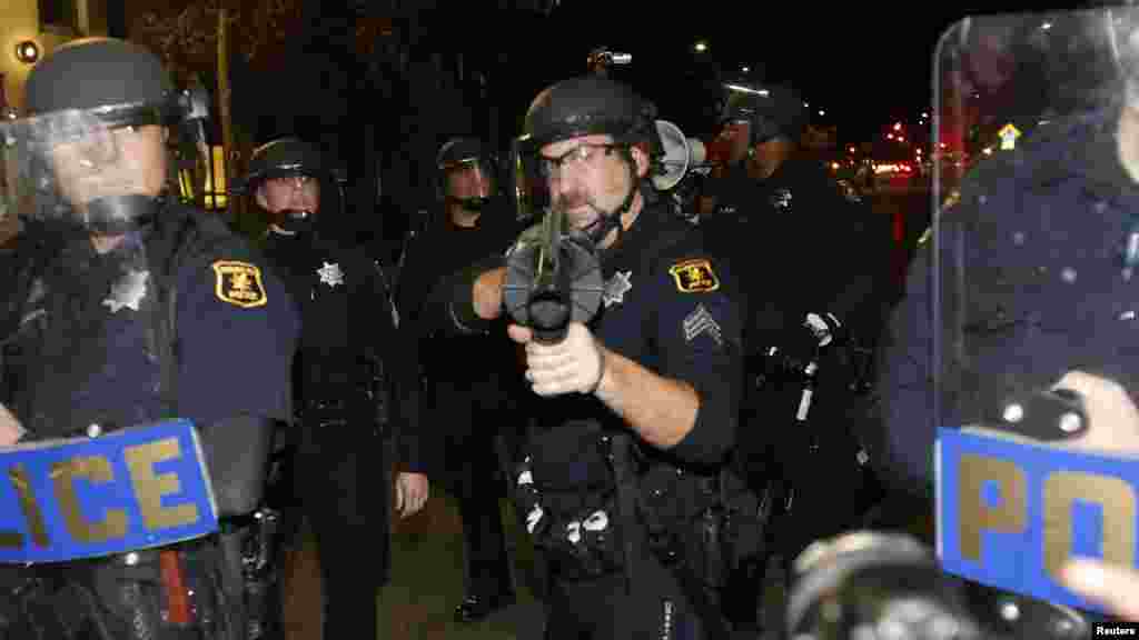 A police officer aims his weapon toward protesters during a march against the New York City grand jury decision to not indict in the death of Eric Garner in Berkeley, California, Dec. 8, 2014.