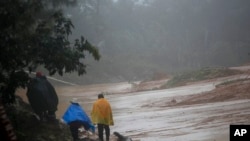 People walk around a road blocked by a landslide in San Cristobal Verapaz, Nov. 7, 2020, in the aftermath of Hurricane Eta. Searchers in Guatemala were digging through mud and debris looking for an estimated 100 people believed buried by a landslide.