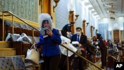 Varias personas buscan protección en la galería de la Cámara de Representantes durante la irrupción de partidarios del presidente Donald Trump en el Capitolio el 6 de enero de 2021.