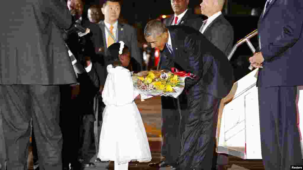 Le président américain Barack Obama reçoit des fleurs d'une jeune fille après son arrivé à l'aéroport international Jomo Kenyatta, Nairobi, 24 juillet 2015.