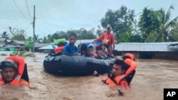 In this photo provided by the Philippine Coast Guard, rescuers use boats to evacuate residents from flooded areas due to Tropical Storm Nalgae at Parang, Maguindanao province, southern Philippines, Oct. 28, 2022.