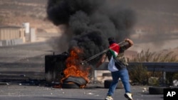 Seorang pedemo Palestina menggunakan ketapel saat bentrokan dengan tentara Israel di Kota Ramallah, Tepi Barat, 20 Oktober 2022. (Foto: Nasser Nasser/AP Photo)