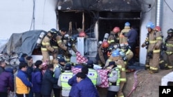 Para petugas kebakaran mengevakuasi para pasien dari rumah sakit yang terbakar di Miryang, Korea Selatan, ke tempat yang lebih aman, 26 Januari 2018.