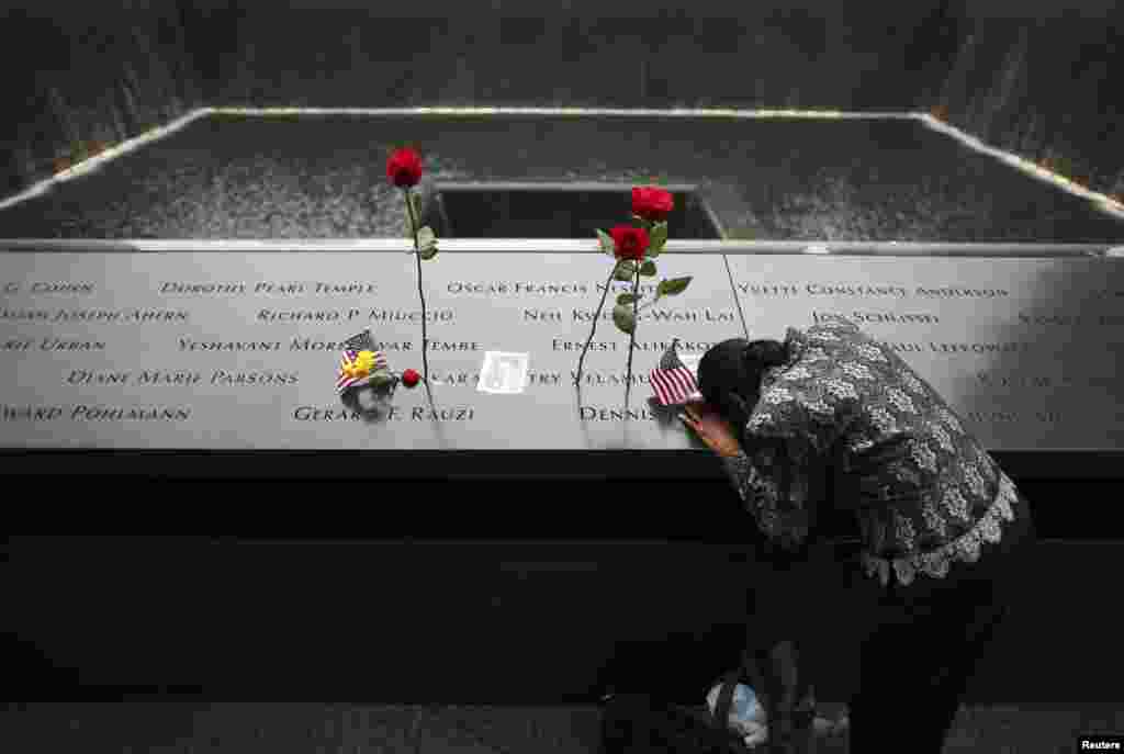 A woman grieves at the site of her husband's inscribed name at the edge of the North Pool during memorial observances on the 13th anniversary of the 9/11 attacks at the site of the World Trade Center in New York, Sept. 11, 2014.