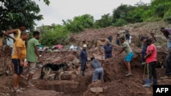 Sejumlah kerabat membantu personel SAR dari Kepolisian Afrika Seltatan (SAPS) membersihkan puing-puing dalam operasi pencaraian sepuluh orang yang hilang saat banjir di wilayah KwaNdengezi, di luar Kota Durban, Afrika selatan, 15 April 2022. (Foto: Phill Magakoe / AFP)