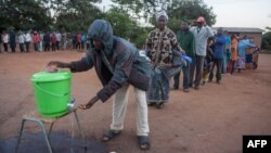 Des personnes font la queue pour se laver les mains afin de se protéger du coronavirus dans un bureau de vote, à Lilongwe, au Malawi, le 23 juin 2020.