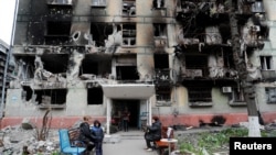 Los residentes se reúnen frente a un edificio residencial gravemente dañado durante la invasión rusa de Ucrania, en la ciudad portuaria sureña de Mariupol, el 21 de abril de 2022.