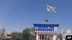 Una bandera talibán ondea en la plaza principal de la ciudad de Kunduz después de los enfrentamientos entre las fuerzas de seguridad talibanes y afganas, en Kunduz, Afganistán, el domingo 8 de agosto de 2021.