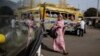 A pedestrian passes a colorful car rapide, with her image reflected in the windshield of a modern Chinese brand King Long bus. Authorities plan to phase out cars rapide by late 2018. (R. Shryock/VOA)