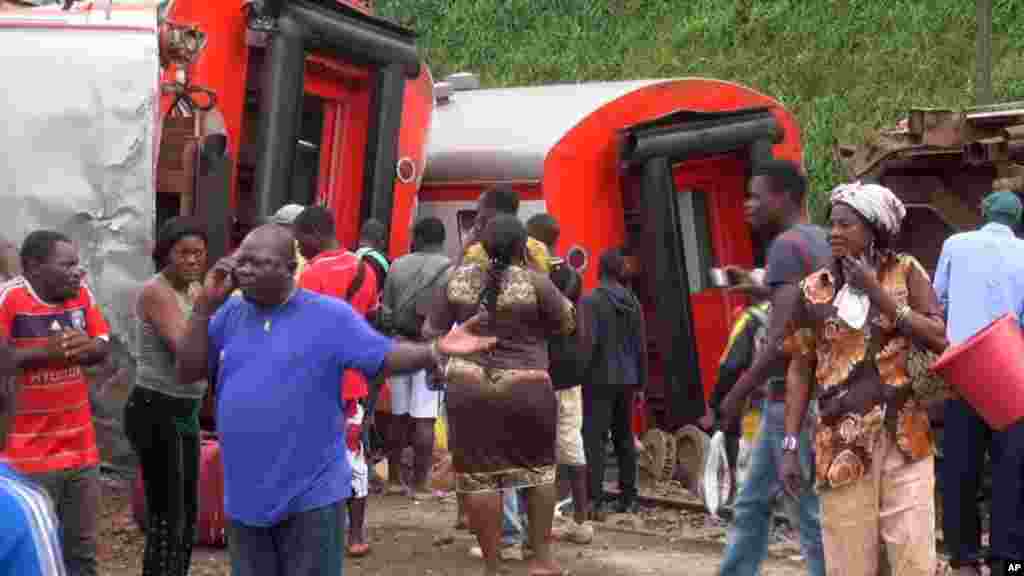 Les rescapés se tiennent à côté des wagons déraillés après l’accident d’un train à l’entrée de la gare Eseka, au Cameroun, 21 octobre 2016.