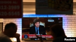 Personas sentadas en un restaurante mientras el presidente de Argentina, Javier Milei, aparece en televisión, en Buenos Aires, Argentina, el 17 de febrero de 2025 