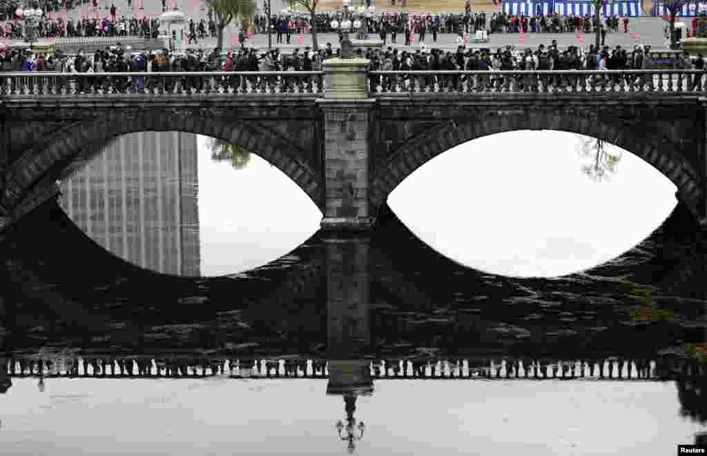 Well-wishers cross a bridge outside the Imperial Palace as they make their way to celebrate Emperor Akihito's 80th birthday in Tokyo, Dec. 23, 2013. 