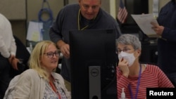 A neutral worker and a Republican and Democratic representative adjudicate ballots cast in the US midterm elections at the Maricopa County Tabulation and Election Center in Phoenix, Arizona, Nov. 9, 2022.