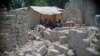 A family uses tarps taken from a refugee camp to get shelter from the sun, with bricks for rebuilding their homes all around them in the PK5 neighborhood of Bangui, Feb. 2017. (Z. Baddorf/VOA)