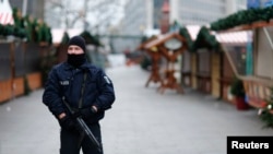 Un police se tient devant le marché de noël Kaiser-Wilhelm-Gedaechtniskirche à Berlin, Allemagne, le 21 décembre 2016.