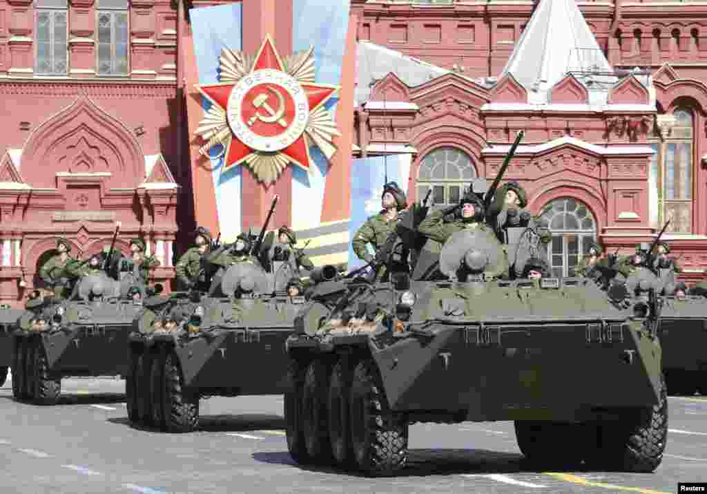 Russian servicemen aboard armored personnel carriers salute during the Victory Day parade in Moscow's Red Square, May 9, 2014.