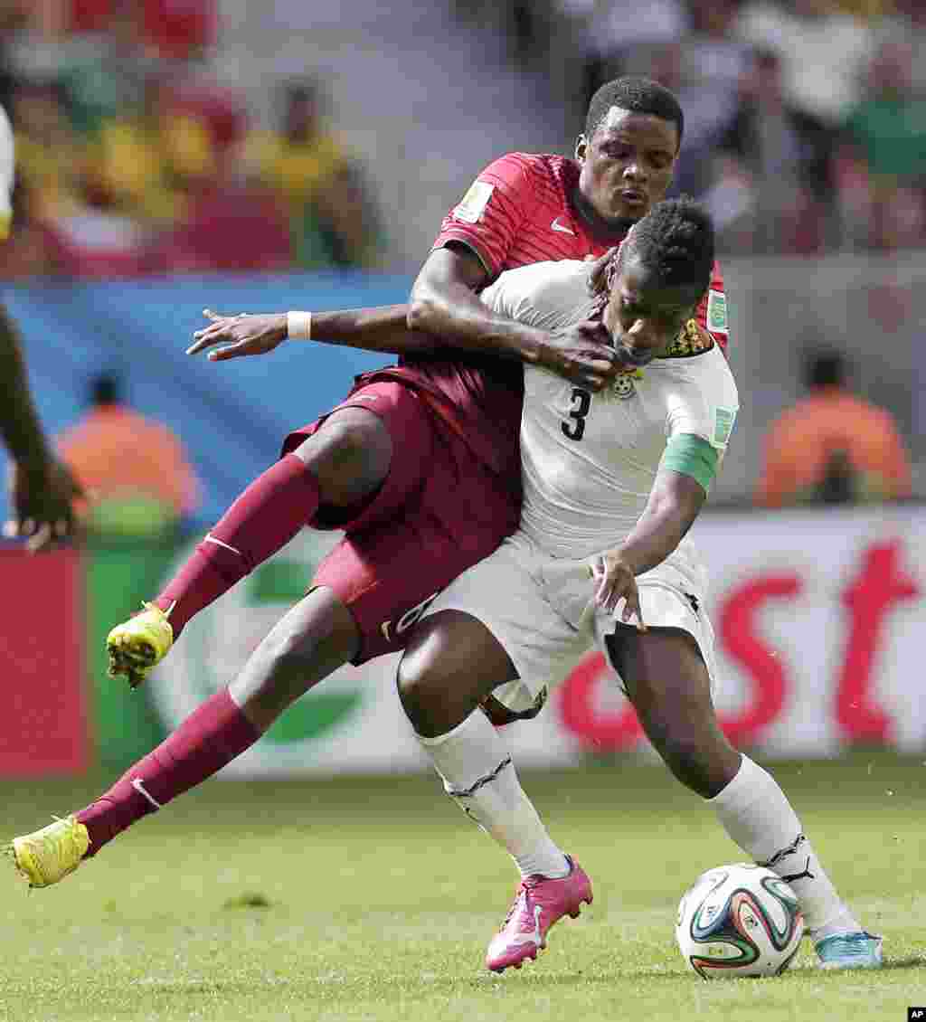Asamoah Gyan du Ghana accroché par William Carvalho du Portugal lors du match de la Coupe du monde du groupe G entre le Portugal et le Ghana au stade Nacional à Brasilia, au Brésil, jeudi 26 Juin 2014.