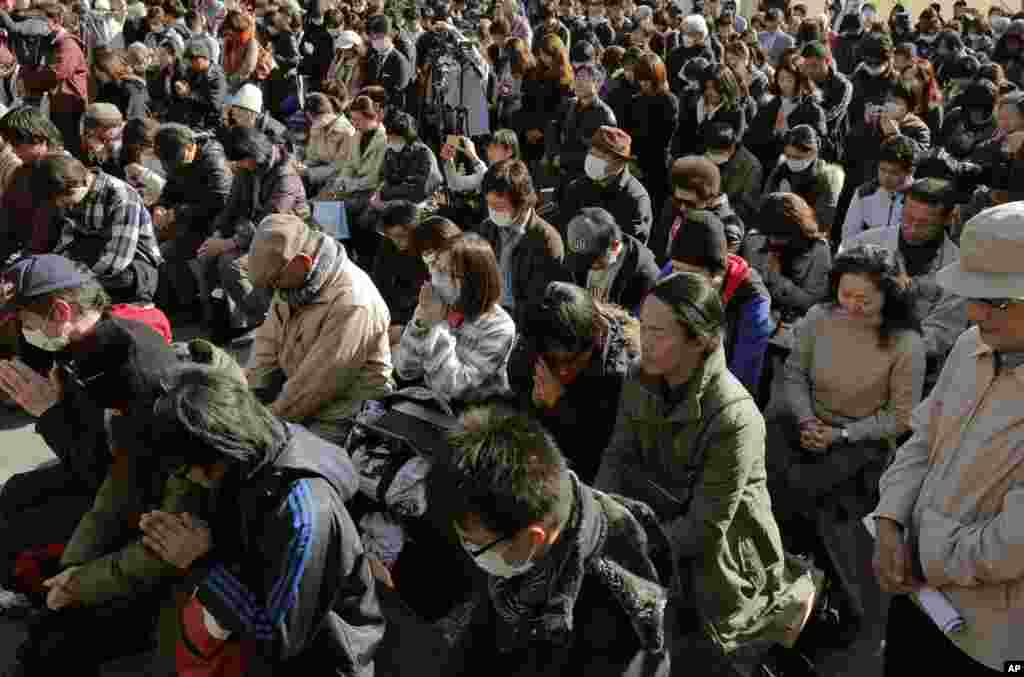 People observe a moment of silence for the victims of the March 11, 2011 earthquake and tsunami during an event at a park in Tokyo, March 11, 2013.