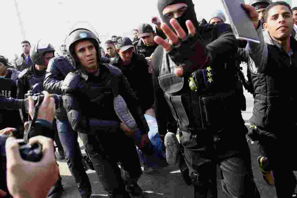 Riot police officers detain a man following clashes between supporters of Egypt's ousted President Mohamed Morsi and police in Cairo, Jan. 8, 2014.
