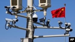 Një flamur kinez valëvitet pranë kamerave të survejimit të montuara në një shtyllë në Sheshin Tiananmen, në Pekin 