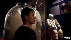 Pengunjung berdiri dekat kapsul Shenzhou-5 yang dipamerkan di Beijing, 6 July 2011 (file:dok).